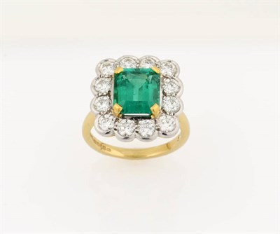 Lot 407 - An 18 Carat Gold Emerald and Diamond Cluster Ring, the emerald-cut emerald held in a yellow...