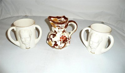 Lot 124 - Two Goss loving cups decorated in relief with William Goss's head and a Masons jug (3)