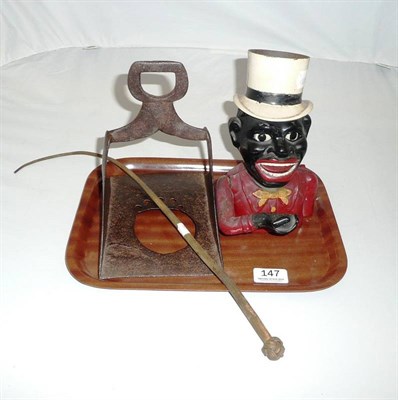 Lot 147 - A cast iron "Jolly Nigger" money bank, a cast iron stirrup and a bull's pizzle whip.