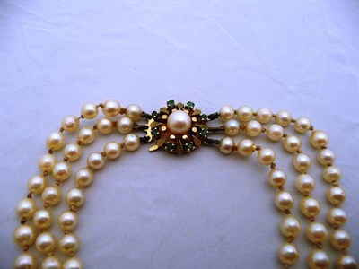 Lot 383 - 9 carat gold and emerald triple-strand pearl necklace