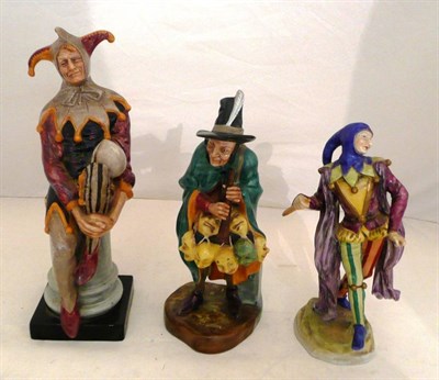 Lot 271 - A Continental figure of a Jester and two Royal Doulton figures 'The Mask Seller' and 'The...