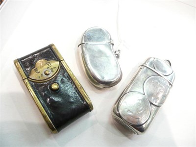 Lot 382 - A silver bean shape vesta case, a coin set vesta case and a brass mounted leather vesta case (3)