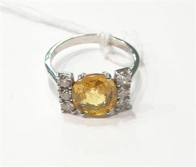 Lot 73 - An 18 carat white gold yellow sapphire and diamond cluster ring