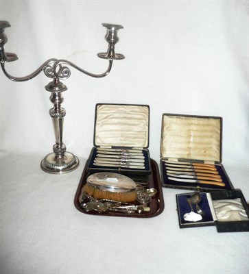 Lot 103 - A plated two branch candelabrum and a tray of mixed silver items including spoons