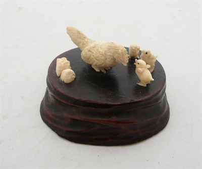 Lot 424 - An ivory group of hen and chicks on wooden base