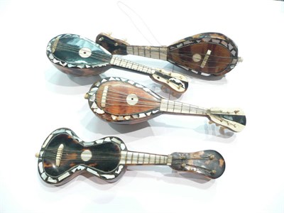 Lot 166 - Three tortoiseshell, bone and mother of pearl inlaid banjos and a similar guitar