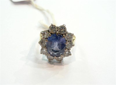 Lot 246 - An 18ct Gold Sapphire and Diamond Cluster Ring, the light blue sapphire sits within a border of...