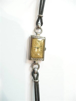 Lot 181 - A diamond set oblong watch on a black cord strap (discoloured dial)