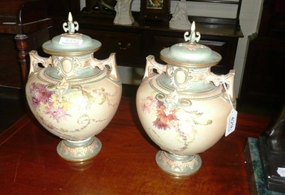 Lot 429 - Pair of Royal Worcester twin handled blush ivory vases with covers painted with flowers