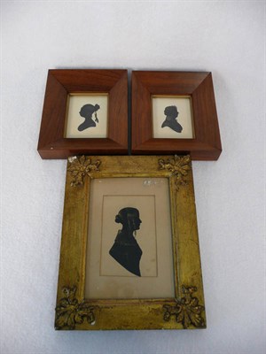 Lot 1240 - A Silhouette of a Lady, circa 1840, cut-out and black painted with gold detail, her hair in a...