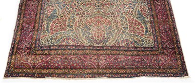 Lot 1380 - A Kirman Carpet, the millefleur field in red, pink, blue and puce on an ivory ground, within a puce