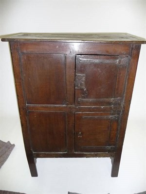 Lot 1384 - An Oak Cupboard, of boarded construction with a panelled front, with an overhung top over a...