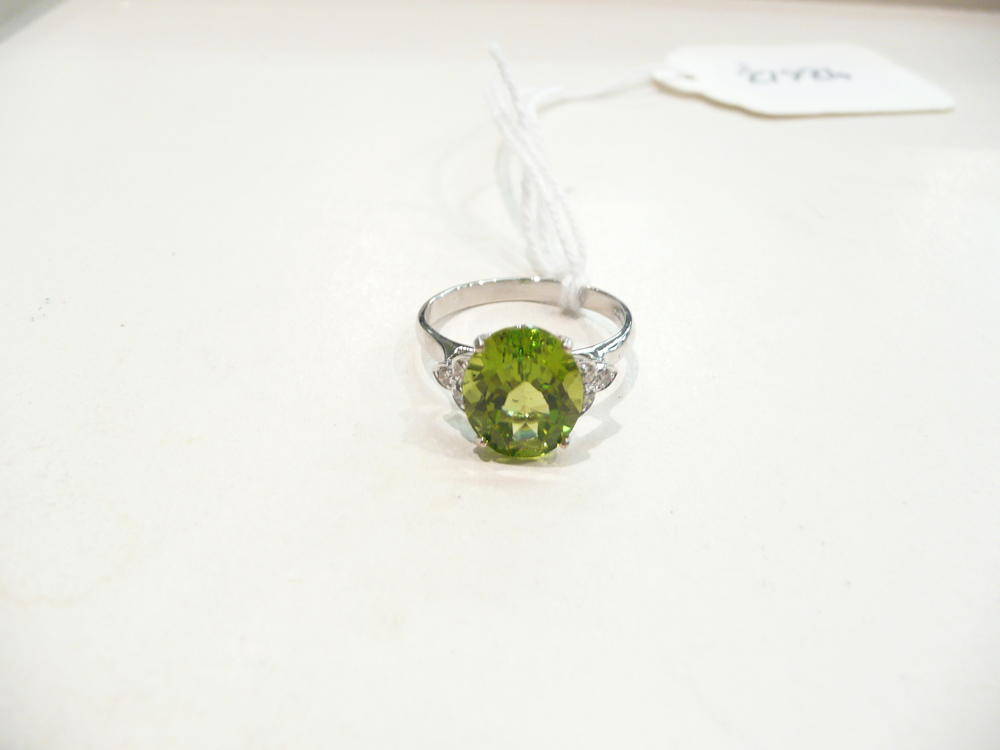 Lot 186 - An 18 carat white gold peridot and diamond cluster ring