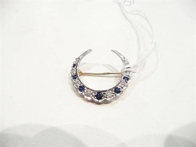 Lot 395 - A 9 carat white gold crescent brooch set with sapphires and diamonds