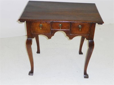 Lot 1413 - A George II Oak Dressing Table, the moulded top over three short drawers in a shaped frieze, on...