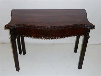 Lot 1433 - A George III Mahogany Foldover Tea Table, the serpentine top with leaf carved edge above a...