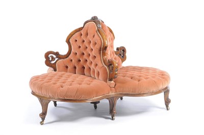 Lot 1480 - A Victorian Walnut Conversation Settee, upholstered in peach button back dralon, the central...