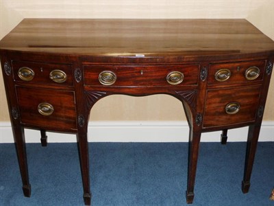 Lot 1505 - A George III Mahogany Bowfront Sideboard, the figured top over a central frieze drawer and...