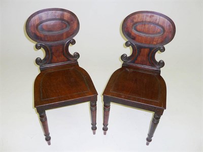 Lot 1527 - A Pair of Regency Mahogany Hall Chairs, the reeded oval backs mounded on volute scrolls, the...