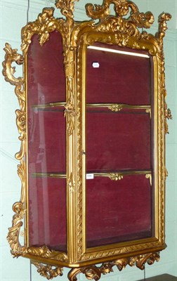 Lot 1596 - A 19th Century Giltwood Hanging Display Cabinet, the rectangular glazed door within a leaf...