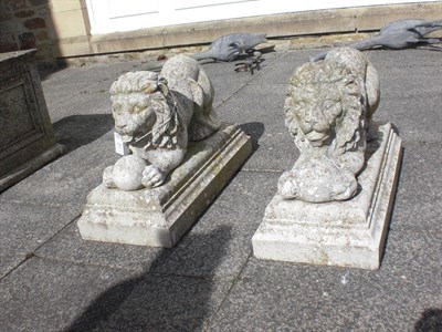 Lot 1739 - A Pair of Composition Garden Statues, modelled as recumbent lions, on moulded bases 67cm long