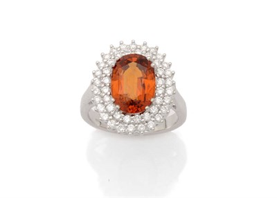 Lot 268 - A Spessartite Garnet and Diamond Cluster Ring, the oval mixed cut central garnet held in pairs...