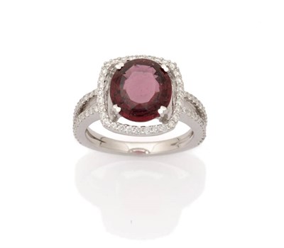 Lot 270 - A Garnet and Diamond Cluster Ring, the oval mixed cut garnet held in a four claw white setting sits