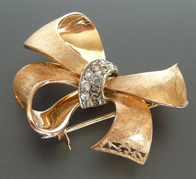 Lot 295 - A Diamond Set Bow Brooch, the textured finish stylised bow has a white central overlay set with...