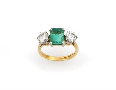 Lot 313 - An Emerald and Diamond Three Stone Ring, an emerald-cut emerald sits between two round...