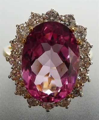 Lot 329 - An 18 Carat Gold Pink Topaz and Diamond Cluster Ring, the oval cut pink topaz in a yellow claw...