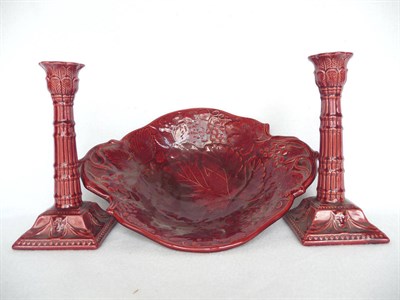 Lot 1047 - A Pair of Burmantofts Candlesticks, moulded with leaves, devils mask and swags, deep red glaze,...