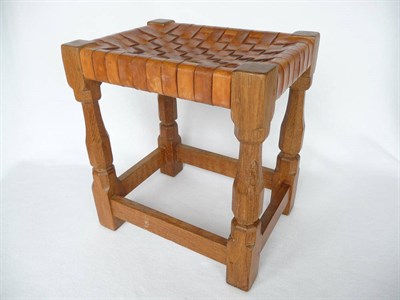 Lot 1095 - A Robert "Mouseman" Thompson Oak Stool, with interwoven leather top, on four octagonal legs...