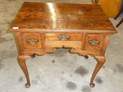 Lot 1154 - A George III Elm Lowboy, the moulded top over three short drawers about the shaped kneehole, on...