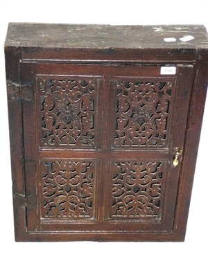 Lot 1162 - A 17th Century Oak Mural Cupboard, the joined door with four fret-pierced foliate panels...