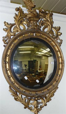 Lot 1243 - A Regency Gilt Convex Mirror, the circular mirror within a reeded, leaf carved and ball mounted...