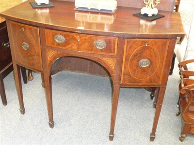 Lot 1262 - A George III Mahogany Bowfront Sideboard, the rectangular crossbanded top above a single frieze...