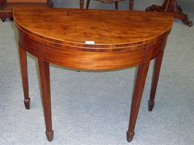 Lot 1295 - A George III Mahogany Demi-Lune Tea Table, the hinged top above a strung frieze, on square tapering