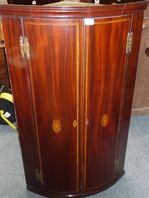 Lot 1297 - A George III Mahogany Bowfront Hanging Corner Cupboard, with a moulded cornice over two doors...