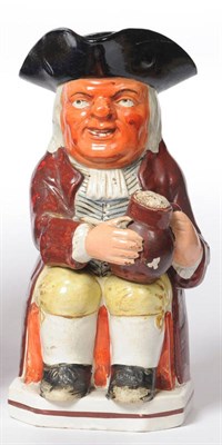 Lot 104 - A Pearlware Pottery Red Faced Toby Jug, circa 1800, the warty faced toper seated wearing black...