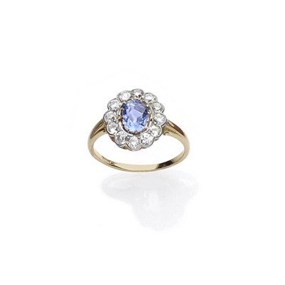 Lot 444 - A Sapphire and Diamond Cluster Ring, the pale blue oval mixed cut sapphire in yellow claw...