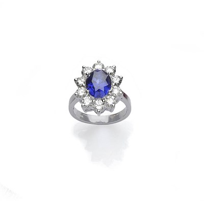 Lot 445 - A Sapphire and Diamond Cluster Ring, an oval mixed cut sapphire within a border of round...