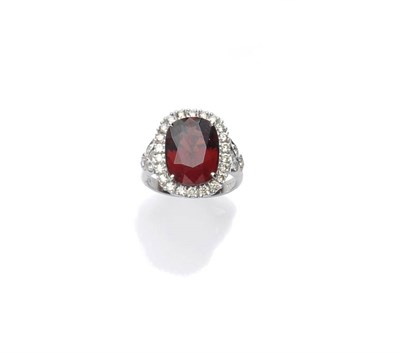 Lot 448 - An 18 Carat White Gold Garnet and Diamond Cluster Ring, the oval mixed cut garnet within a...