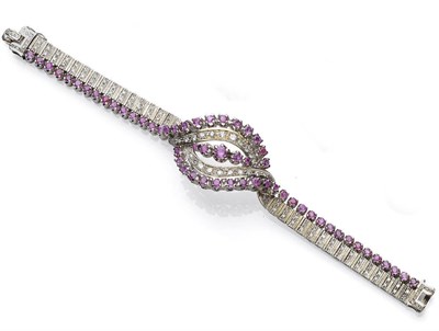 Lot 453 - A Ruby and Diamond Bracelet, two lines of rubies meet at a central swirl, with round brilliant...