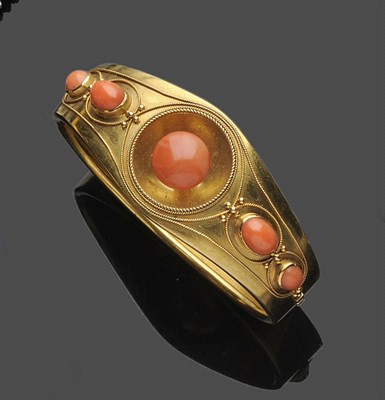 Lot 484 - A Victorian Coral Bangle, the graduated bangle set with a round cabochon coral to the centre,...