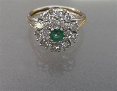 Lot 498 - An Emerald and Diamond Cluster Ring, a central round cut emerald sits within two rows of round...