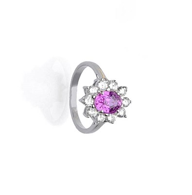 Lot 504 - A Pink Sapphire and Diamond Cluster Ring, the oval mixed cut pink sapphire within a border of round