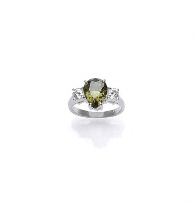 Lot 509 - A Demantoid Garnet and Diamond Three Stone Ring, the pear cut garnet flanked by a round...