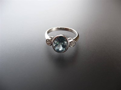 Lot 520 - An Aquamarine and Diamond Three Stone Ring, the oval cut aquamarine sits between two round...