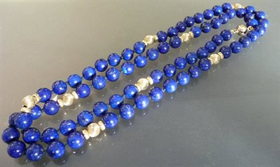 Lot 538 - A Lapis Lazuli Necklace, spherical beads on a knotted strand, interspersed by trios of gold...