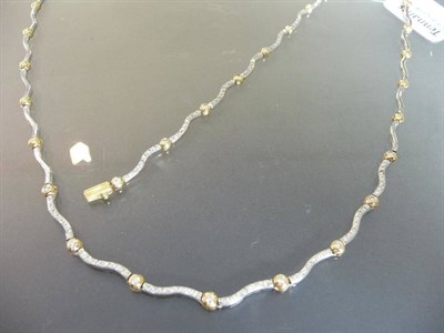 Lot 541 - A Two Colour Diamond Necklace and Bracelet, of wavy white polished links spaced by yellow...